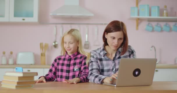 家庭で働く若い母親は、娘のソーシャルネットワークモバイルアプリケーションに疲れています。働くお母さん邪魔し、積極的な子供に悩まされる. — ストック動画