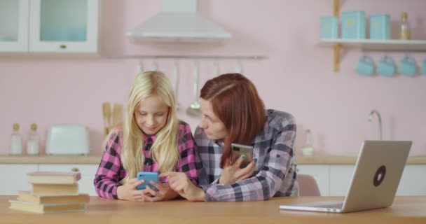 Ung vuxen kvinna och preteen flicka skrattar medan du tittar på video på mobiltelefon ansökan. Familjen har kul att surfa internet tillsammans. Mamma och dotter stannar hemma.. — Stockvideo