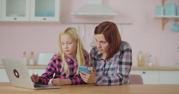 Mor og datter surfer på nettet i mobilappen hjemme. Familie av to som bruker en mobiltelefon. – stockvideo