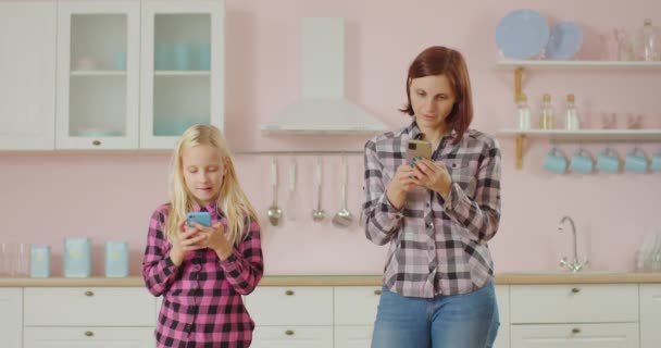 Jonge dertiger jaren moeder en pre-tiener dochter surfen op sociale media, sms 'en berichten met behulp van mobiele telefoons. Familie surfen op internet met behulp van gadgets. — Stockvideo