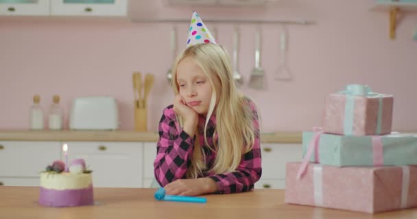 Niña molesta celebrando cumpleaños sola en casa. Triste joven cumpleañera pidiendo un deseo y soplando la luz de la vela sin invitados en la fiesta de cumpleaños. — Vídeos de Stock