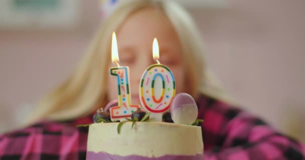 Close up of little girl blowing out color candles with number 10 on birthday cake in slow motion. Ten years old girl celebrates birthday. — Stock Video