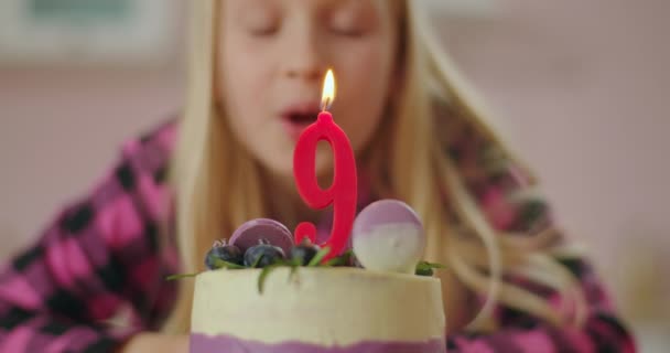 Close up de menina soprando vela vermelha com o número 9 no bolo de aniversário em câmera lenta. Nove anos de idade menina celebra aniversário. — Vídeo de Stock