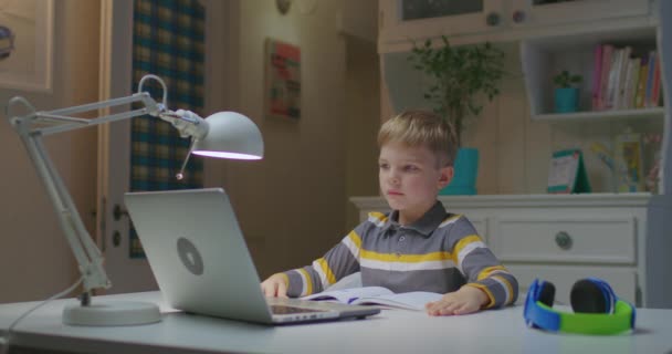 Niño de edad elemental que estudia en línea en casa. Niño hablando con el profesor en línea por ordenador portátil. Educación en línea y aprendizaje a distancia para niños. — Vídeos de Stock