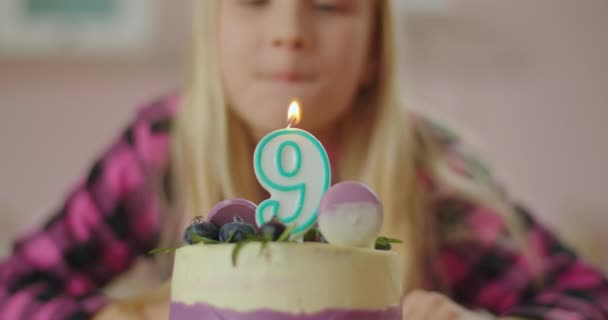 Close-up van klein meisje blaast kaars uit met nummer 9 op verjaardagstaart in slow motion. Negen jaar oud meisje viert verjaardag. — Stockvideo