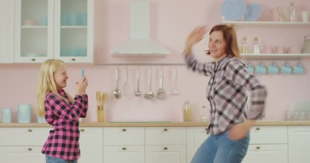 Familj till unga vuxna mamma och skolbarn som spelar in rolig dans på mobilkamera för mobilapplikation. Dansande mor och dotter. — Stockvideo