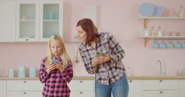 Jóvenes de 30 años madre y pre hija adolescente navegando por las redes sociales, mensajes de texto utilizando teléfonos móviles. Familia navegar por Internet utilizando gadgets. — Vídeos de Stock