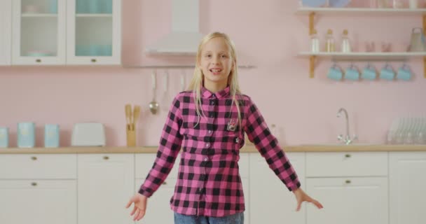 Usmívající se dívka tančící moderní tanec dívající se do kamery. Pohled na dětské tance pro populární sociální sítě. Holčička nahrává video tance. — Stock video