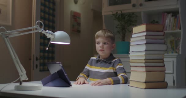 Vorschulkind wählt Papierbücher oder Tablet-Computer mit Augen. Junge zieht Tablet Büchern vor. Online-Lernen ist die Zukunft der Bildung. — Stockvideo