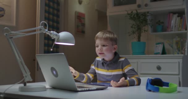 Дошкільна дитина малює на планшетному комп'ютері під час навчання онлайн вдома. Онлайн-освіта та дистанційне навчання для дітей. Молодий хлопчик робить домашнє завдання з планшетом і ноутбуком .. — стокове відео
