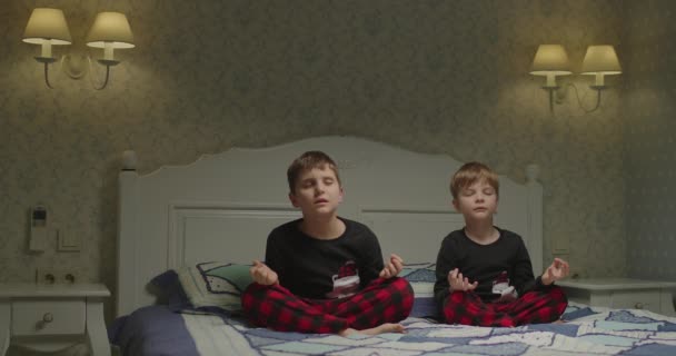 Les enfants font de la méditation avant d'aller au lit. Frères et sœurs respirant les yeux fermés pour se calmer avant de dormir. — Video