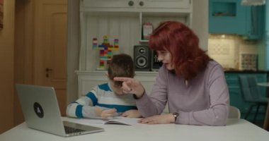 Anne, otizmli oğluna internet okulunda ödev yapması için yardım ediyor. Otizm spektrum bozukluğu eğitimi evde. İnternetten evde eğitim. 