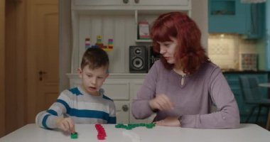 Anne otizmli oğluna renk başlıklarını ayırmayı öğretiyor. Otizm terapisti evde çalışıyor. Otizm spektrum bozukluğu eğitim süreci. Otistik çocuk öğrenimi.
