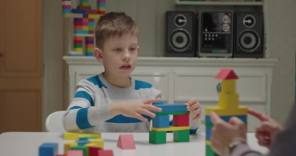 Edificio de niño autista con bloques de madera de color. El maestro asigna una tarea al alumno con autismo. Terapeuta de análisis de comportamiento aplicado que trabaja con un niño. — Vídeos de Stock