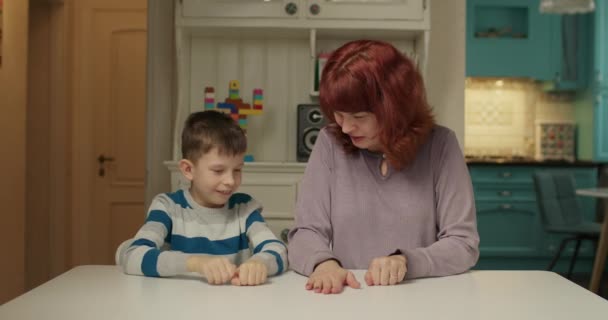 自閉症の子供と指ゲームをしている自閉症のセラピスト。家庭で母親と一緒に勉強する自閉症の少年。自閉症の子供は注意と協調に焦点を当てることを学ぶ. — ストック動画