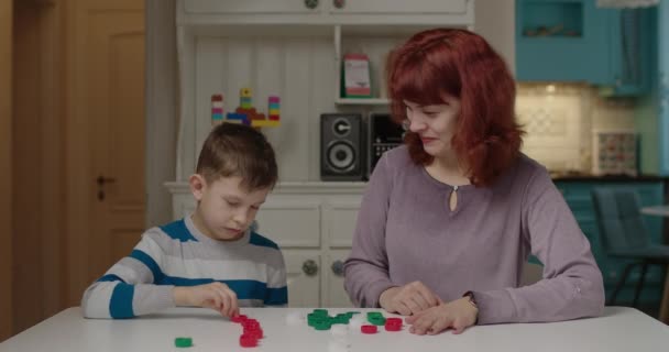 色の帽子を分類する自閉症の息子を教える若い母親。自閉症のセラピストは自宅で働いています。自閉症スペクトラム障害教育プロセス. — ストック動画