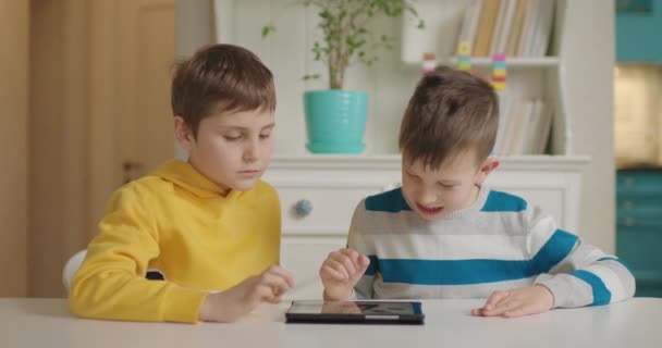 Dos niños con autismo usando una tableta para la aplicación de la educación. Educación sobre el trastorno del espectro autista en línea. — Vídeo de stock