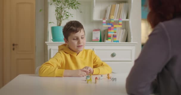 Аутист-терапевт навчає дитину аутизму. Шкільний хлопчик з аутизмом вивчає тварин з репетитором. Освіта аутистичного спектру розладів вдома . — стокове відео