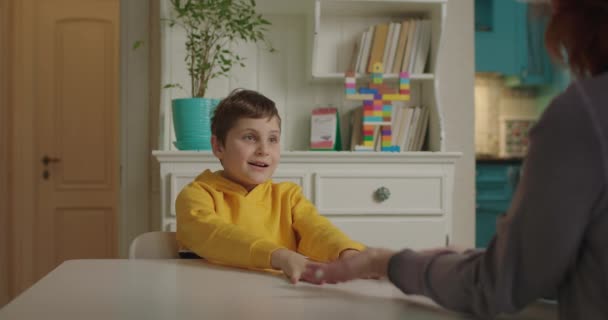 Okulda otizm terapistiyle çalışan bir çocuk evde masada oturuyor. Otizm spektrum bozukluğu eğitim süreci. Konuşma terapisti oğlanla çalışıyor.. — Stok video