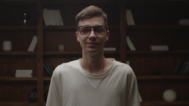 Portrait of smiling confident millennial man in eye glasses looking at camera in the dark room. Man taking of eyeglasses looking at camera and smiling. — Stock Video