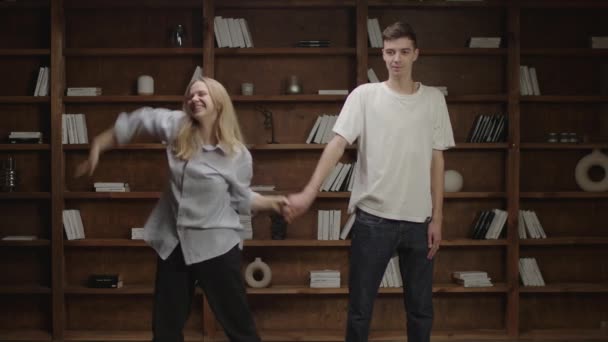 Millennials danse danse drôle au salon. 20 ans homme et femme s'amusent ensemble à la maison. Agitant les mains pendant que la danse drôle se déplace. — Video