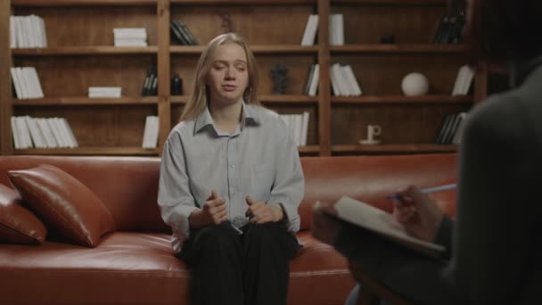 Zwanzigjährige Frau spricht mit Psychotherapeutin auf Couch über Beziehungsprobleme. Millennium-Familienprobleme. Blonde Dame spricht mit Psychologe. — Stockvideo