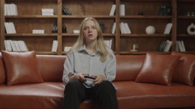 Milenyum kadını çok duygusal oyunlar oynuyor. 20 'li yaşlarda bekar bir kadın video oyunu bağımlısı. Evdeki koltukta oturan kişi..
