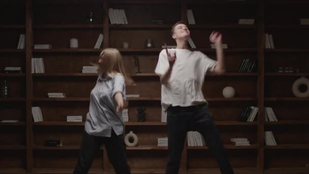 Ung man och kvinna dansar i biblioteket hemma. Pojkvännen och flickvännen har kul tillsammans. Familjen stannar hemma och njuter av tiden tillsammans. — Stockvideo