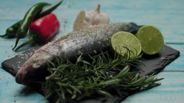 Gyógynövényeket öntök friss halakra. Felkészülés tengeri sügér grillezett hal főzésére. Fűszerekkel és sóval főtt hal. Díszített halétel. — Stock videók