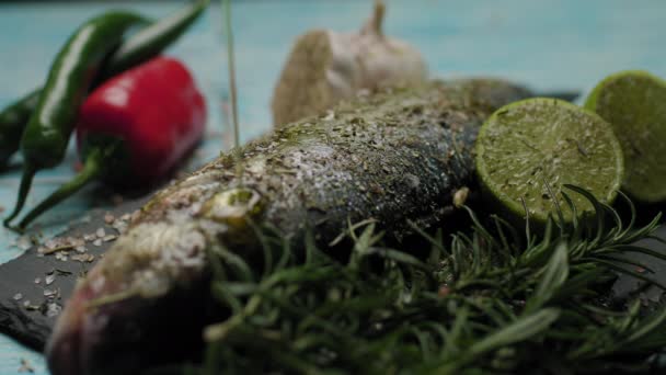 Verter aceite de oliva sobre el pescado fresco. Preparación para cocinar pescado de lubina a la parrilla. Cocinar pescado con especias y sal. Plato de pescado decorado. Primer plano del vertido de aceite de oliva. — Vídeo de stock