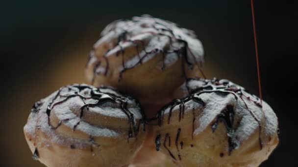 Profiteroles con crema de natillas vertiendo con cobertura de chocolate. Cierre de pasteles con cobertura de chocolate. — Vídeos de Stock