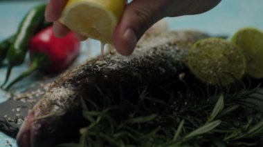 Taze balığa limon suyu sıkıyorum. Izgarada levrek pişirme hazırlığı. Baharatlı ve tuzlu balık pişirmek. Madalyalı balık yemeği. Limon sıkmayı kapat..