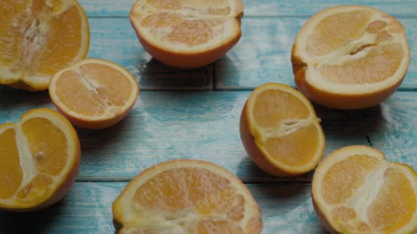 Orangenfruchthälften fallen auf den Tisch mit vielen reifen Orangenstücken. Saftige Zitrusfrüchte auf blauem Schreibtisch. — Stockvideo