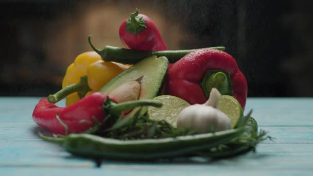 Čerstvá zelenina cákající vodou. Červená a žlutá paprika, avokádo, limetka na stole. — Stock video