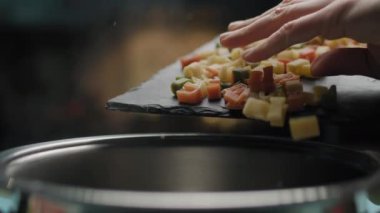 Kadın eli, alfabe renginde makarnayı kaynar suyla tavaya döküyor. Makarna pişirmeye yakın olsun. Çocuklar için ABC makarna.
