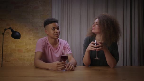 Jeune couple mixte buvant du vin rouge et parlant assis ensemble à la maison. Happy millennials rencontres avec le vin. — Video