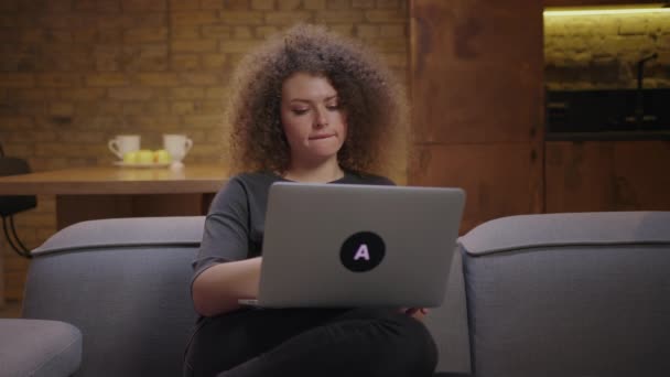 Egy fiatal nő befejezte a munkáját és bezárta a laptopját a kanapén ülve. Millenniumi női dolgozó otthonról a laptop. — Stock videók