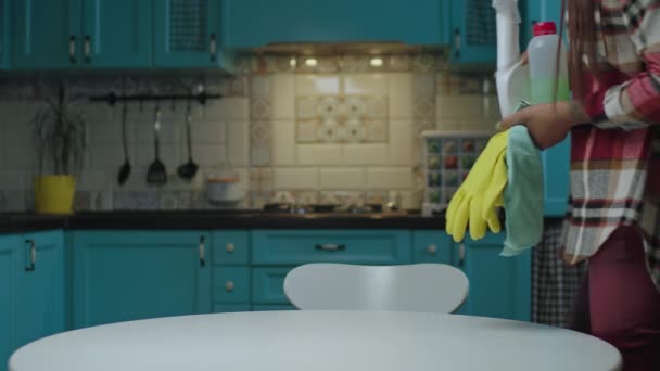 20s Afro-Amerikaanse vrouw moe van het huishouden komen met gele rubberen handschoenen en wasmiddelen zitten aan tafel bij blauwe keuken. — Stockvideo