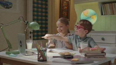 Komik çocuklar kurabiye yiyip, süt içiyorlar ve bilgisayarla konuşuyorlar. Kardeşler birlikte oynuyorlar ve online arkadaşlarla konuşuyorlar..