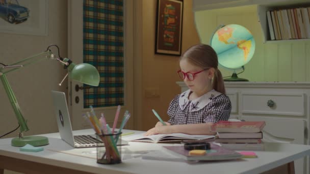 Écolière heureux de terminer la leçon d'école Internet et commence à jouer sur téléphone mobile. Jeune fille mignonne portant des lunettes à l'aide d'un téléphone mobile après l'école en ligne. — Video