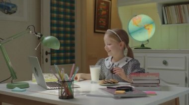 Mutlu liseli kız arkadaşlarıyla internette konuşuyor, kurabiye yiyor ve süt içiyor. Uzaktan eğitim gören çocukların hayatı. Atıştırmalıklarla çevrimiçi okul arası.