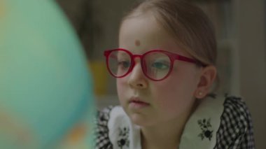 Evinde Dünya küresi okuyan okul kızlarına yakın çekim yap. Gözlük takan meraklı çocuk Dünya gezegenini keşfediyor..