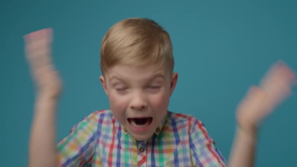 Geschokt kind met hoofd en handen op een blauwe achtergrond. peuter tonen shock emotie kijken naar camera. — Stockvideo