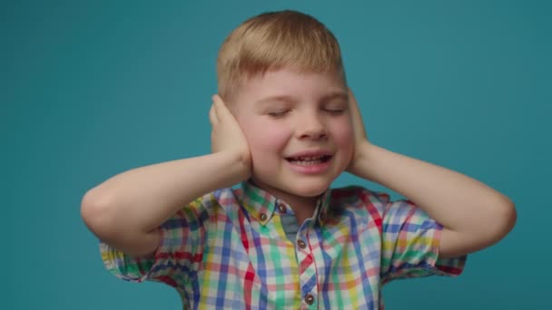 Roztomilé dítě se zavřenýma očima a ušima křičící NE stojící na modrém pozadí. Ten kluk nechce nic slyšet. Dítě křičí Neslyším tě. — Stock video