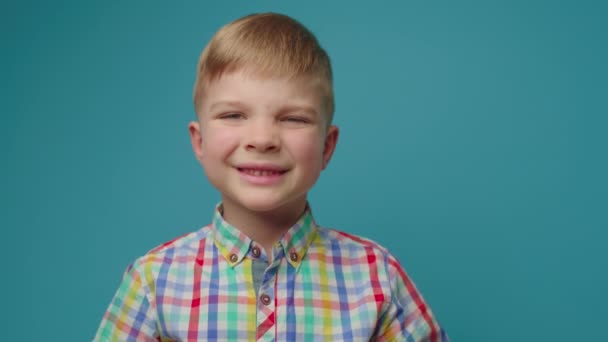 Niño preescolar cerrando las orejas con las manos y gritando NO mirando a la cámara de pie sobre fondo azul. El chico se niega a escuchar algo.. — Vídeos de Stock