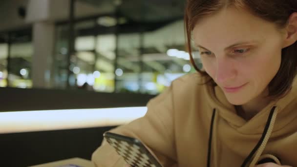Close up af 30 'erne kvinde ved hjælp af mobiltelefon til browsing net sidder i cafe. Koncentreret ung voksen kvinde med celle i hånden. – Stock-video