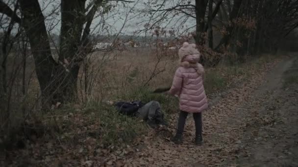 暗い秋の森の中で屋外で遊んでいる子供たち。笑顔の少年は冬のジャケットで女の子と遊ぶ。地面に寝そべっている子供. — ストック動画