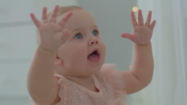 Söt flicka med blå ögon som håller upp händerna och ler. Närbild av glada lilla flicka viftande händer. — Stockvideo