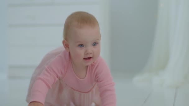 Söt leende bebis flicka krypa på golvet på vita barn rum. Glad 10 månader gammal baby kryper. — Stockvideo