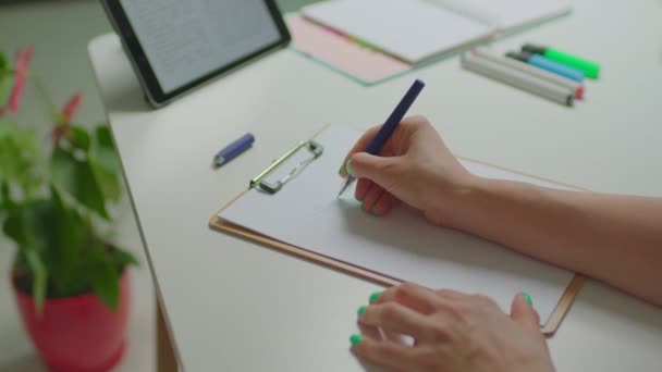 Ženská ruční psaní Plány pro dnešek podepsat na list papíru pomocí pera sedí za stolem s počítačem tabletu. — Stock video